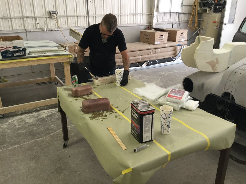 worker applying reside to car parts on workbench
