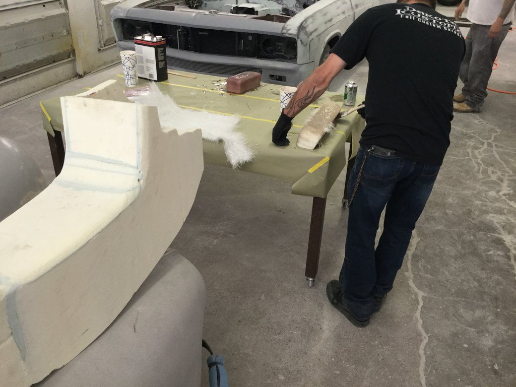worker applying reside to car parts on workbench