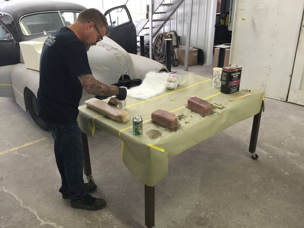 worker applying reside to car parts on workbench
