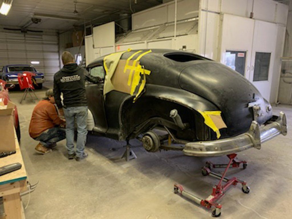 rear view of car with yellow tap on car parts rear wheels removed and rear suspended