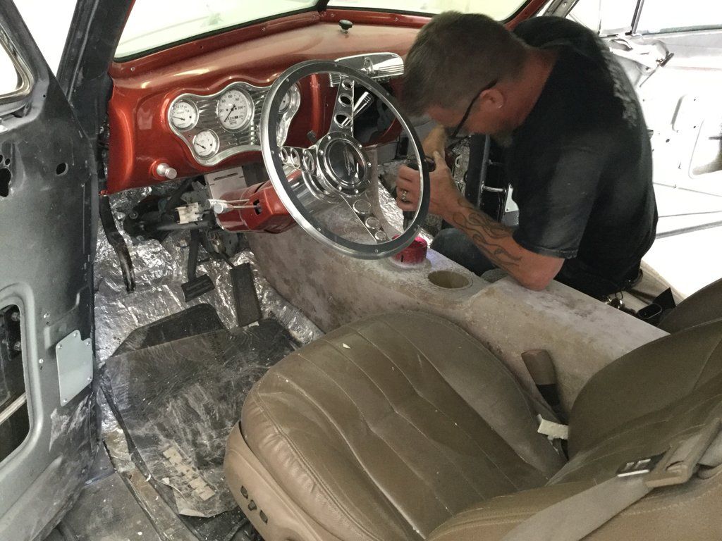 interview view of car with chrome steering wheel with worker inspecting central console