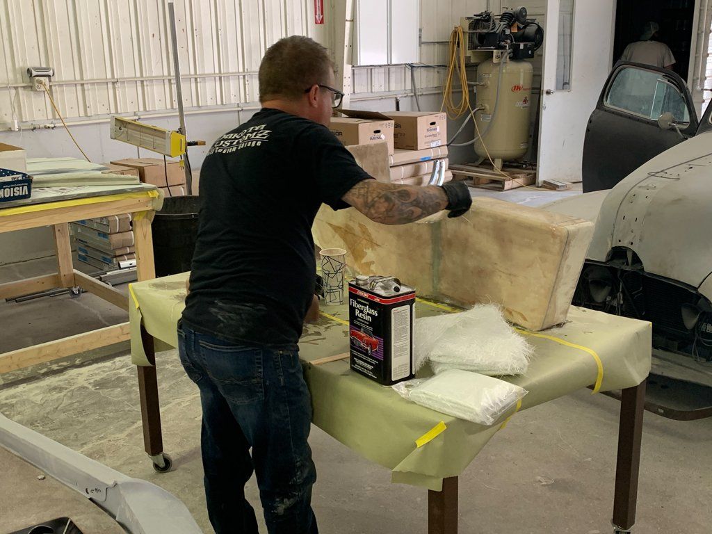 worker applying resin to wooden car parts
