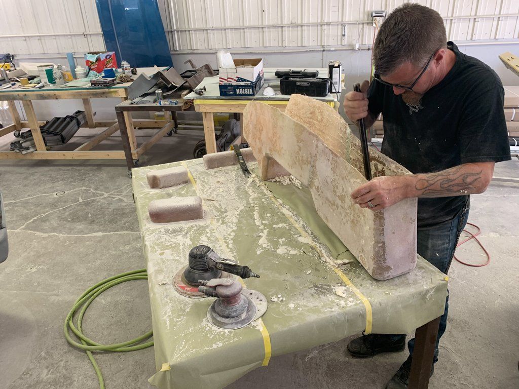 worker chiseling wooden center console mold on workbench