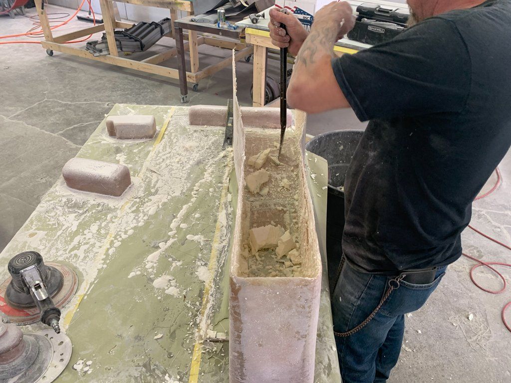 worker chiseling out wooden center console on workbench