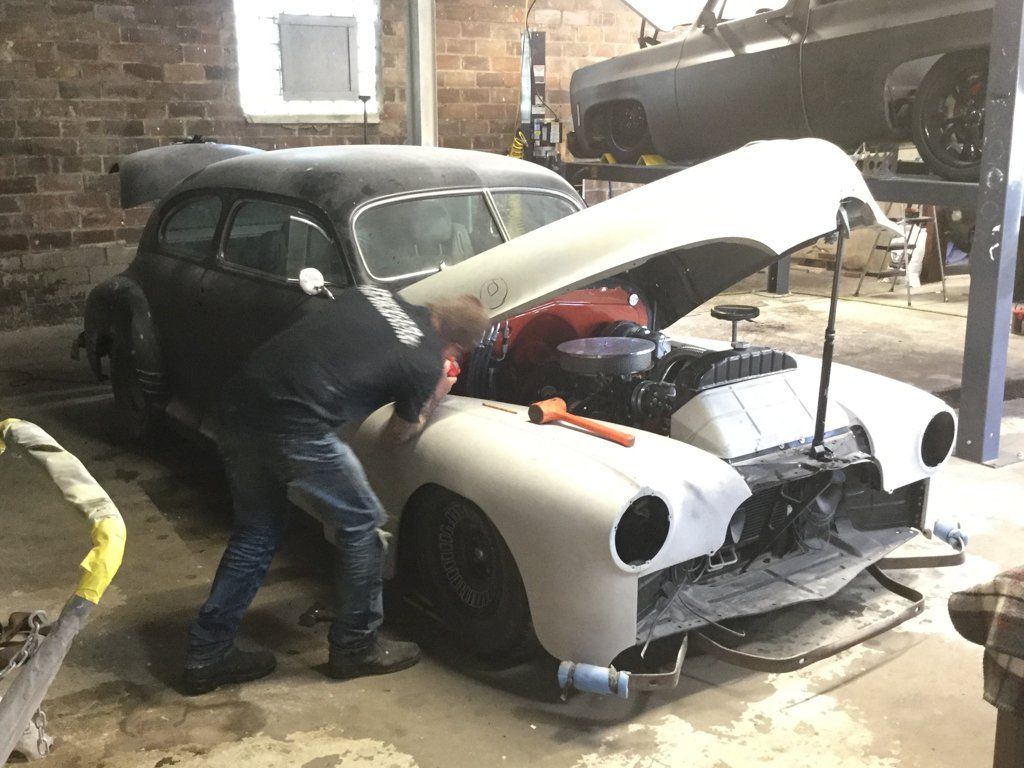 front view of car with hood propped up with wooden stake
