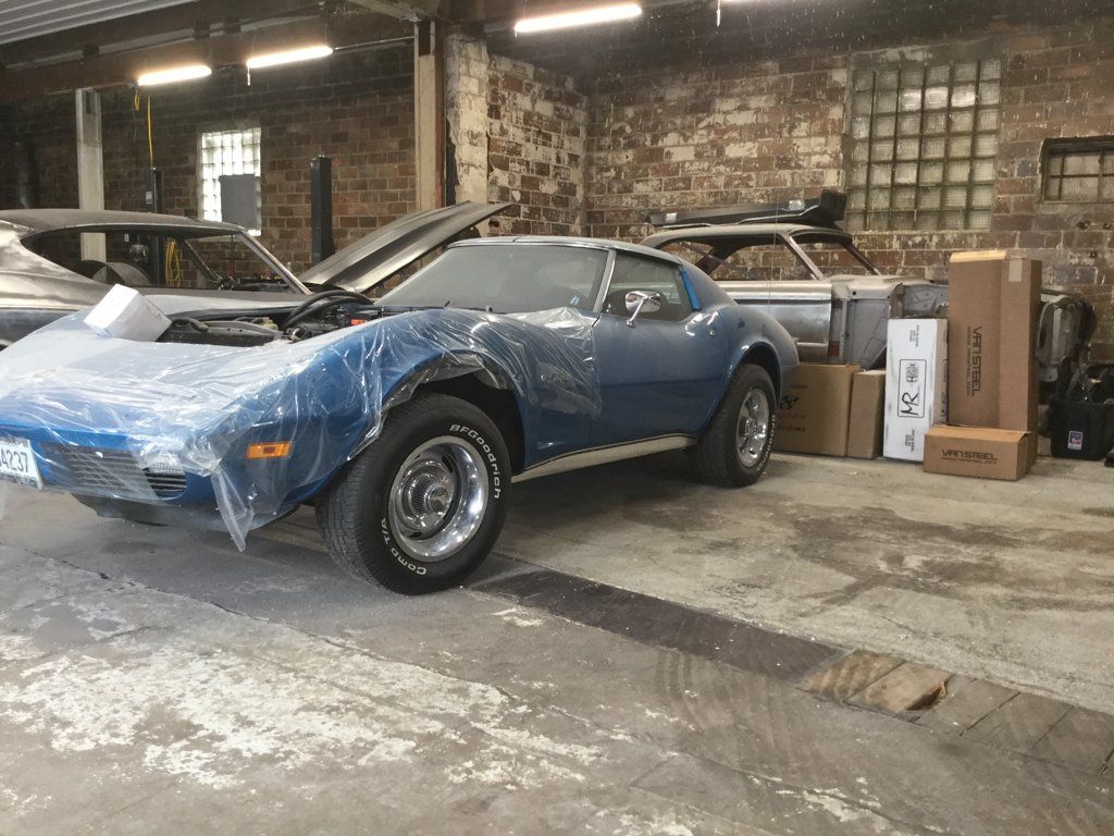 car covered in plastic in corner of garage