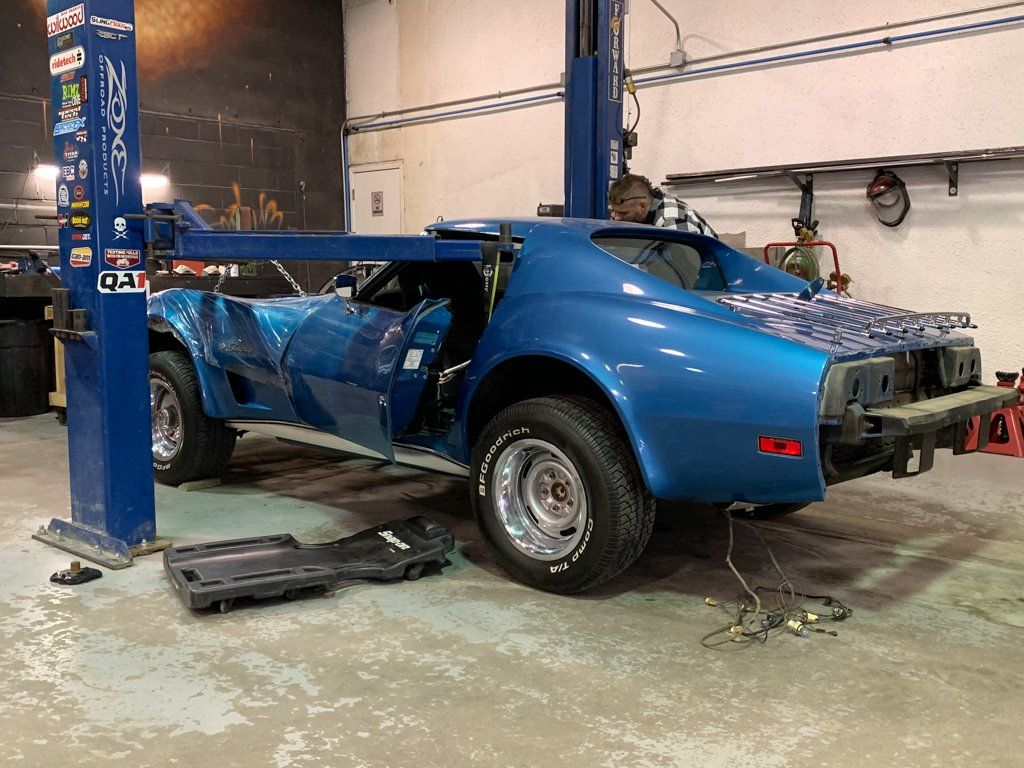 car body being serviced on service bay with steel beam going through windows of car body