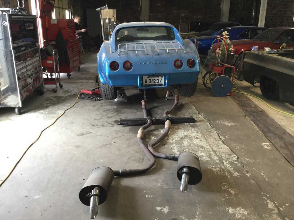 car rear with exhaust pipes laid out on ground