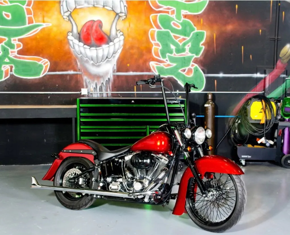 customized red and black chopper side view in front of dakota kustomz graffiti skull wall art