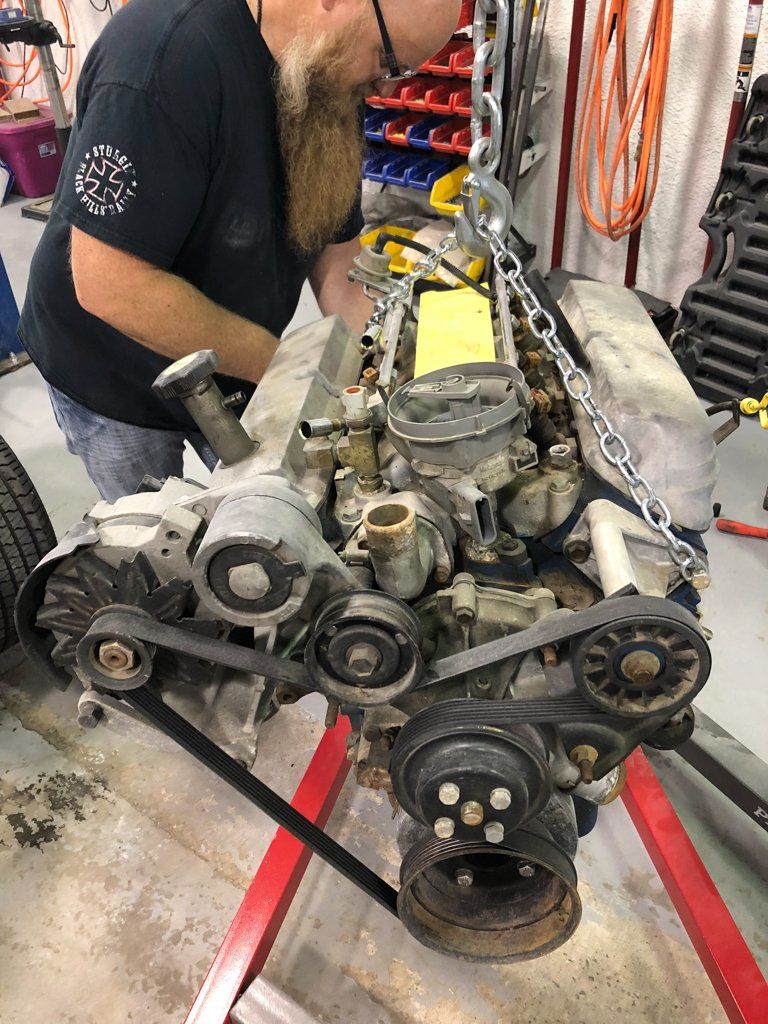 mechanic working on engine while it's suspended