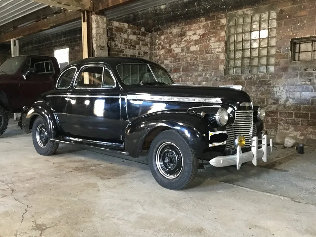 custom black 1940 deluxe special coupe in front of service bay