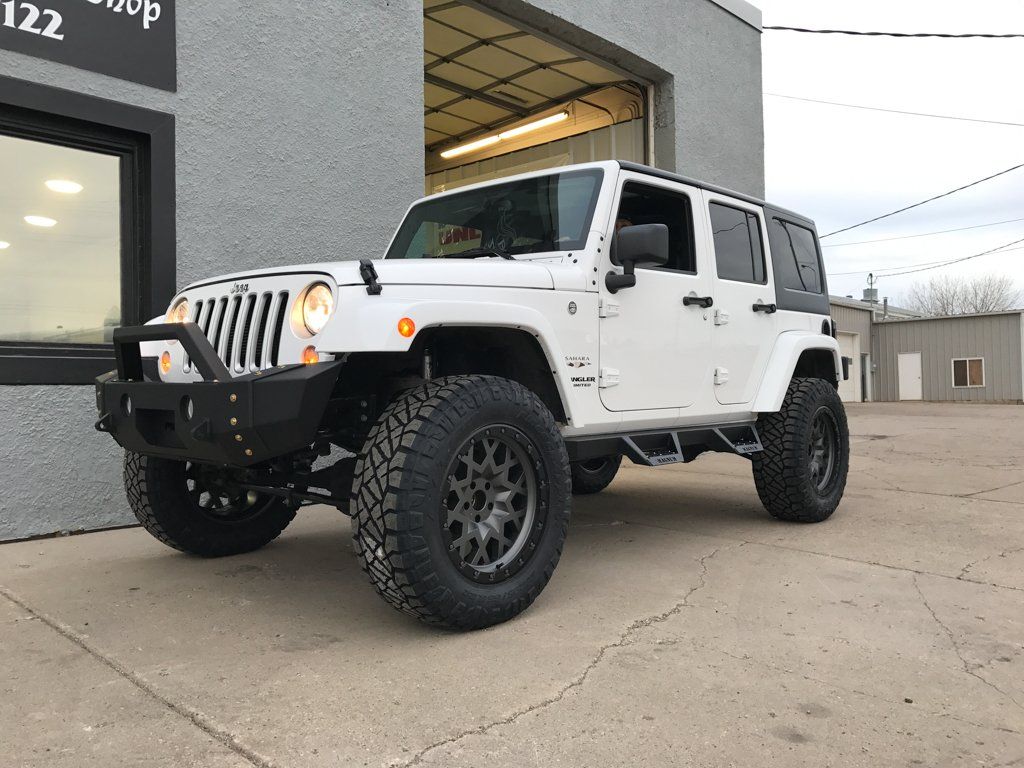 custom white jeep wrangler with lift kit in front of dakota kustomz garage
