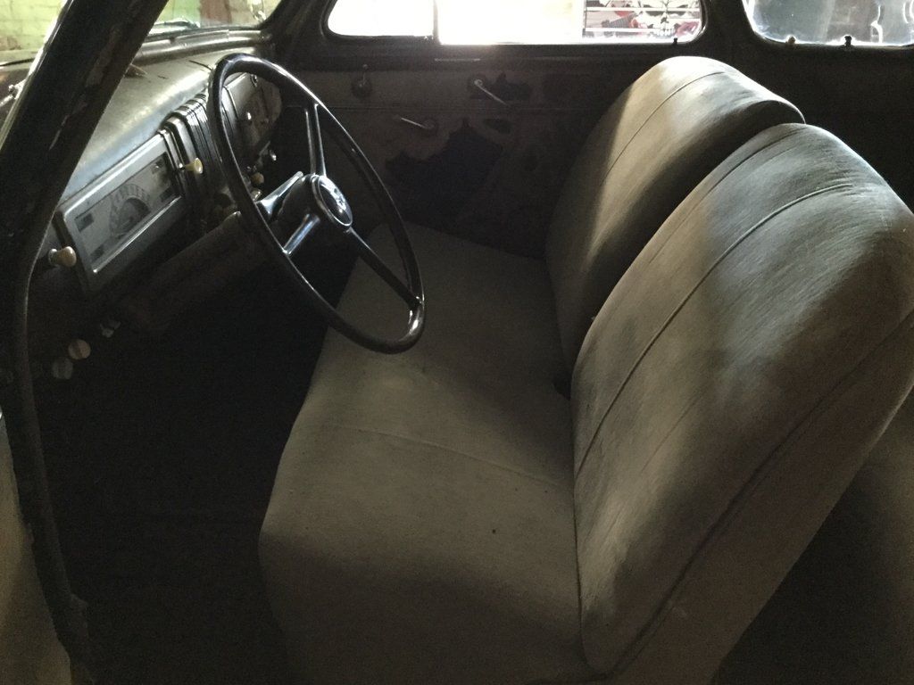 view of front seats and steering wheel of black 1940 chevy special deluxe coupe