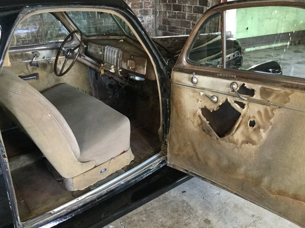 black 1940 chevy special deluxe coupe with torn door and view of driver seat