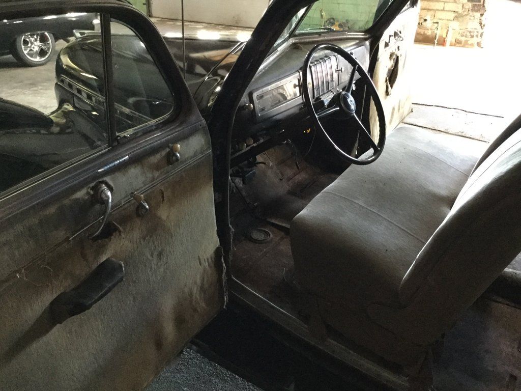 black 1940 chevy special deluxe coupe with door open and view of steering wheel and driver seat