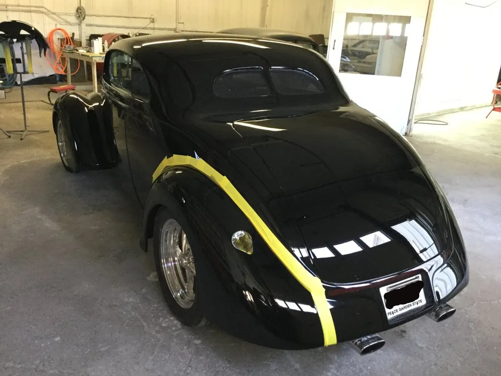 rear view of custom black 1937 ford tudor hot rod with tape on rear fender