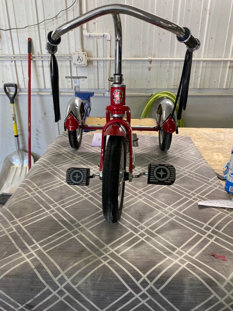 front view of custom red tricycle on workbench with seat removed