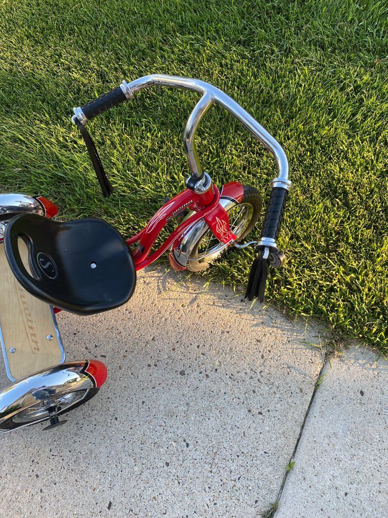 top view of custom red tricycle on sidewalk and grass