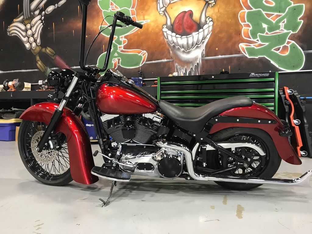 customized red and black chopper side view in front of dakota kustomz graffiti wall art
