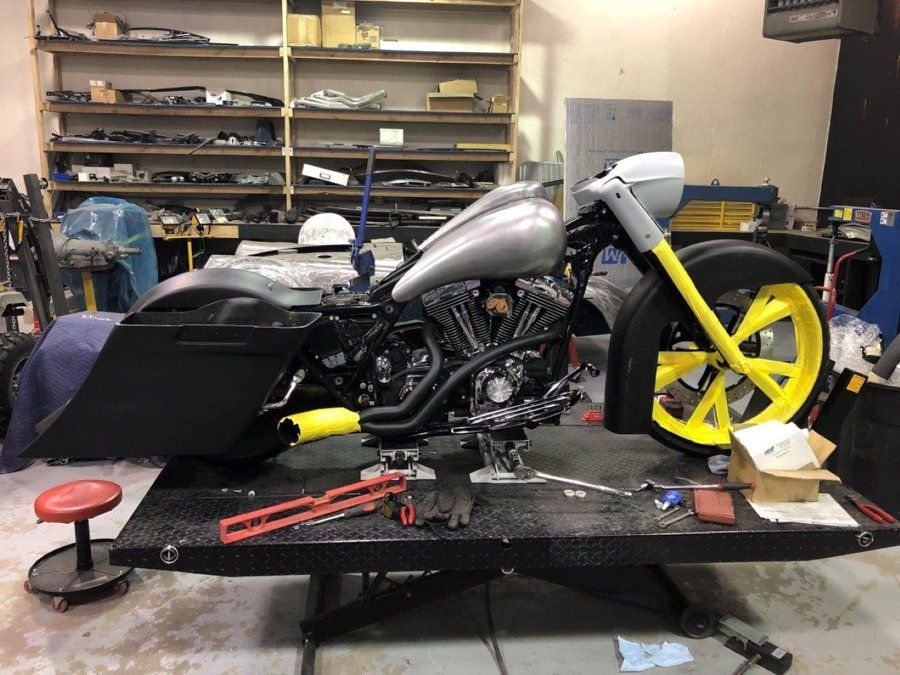 side view of black chopper being customzed front wheel covered in yellow tape
