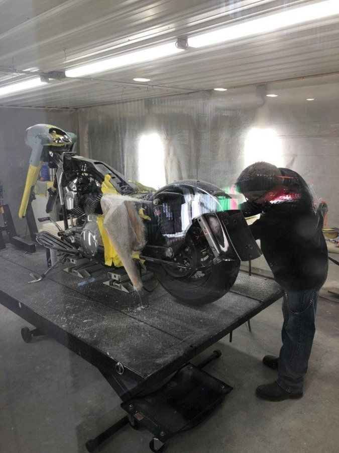 worker detailing black chopper on workbench