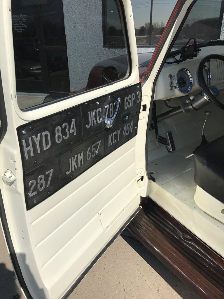driver side view of red customized pickup door open with license plates in the interior