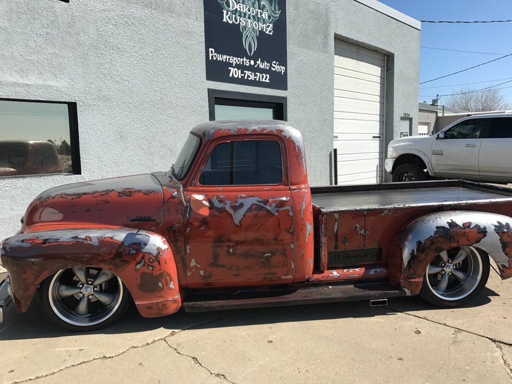 side view of red customized pickup outside of dakota kustomz office