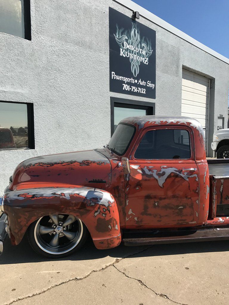 side view of red customized pickup outside dakota kustomz office