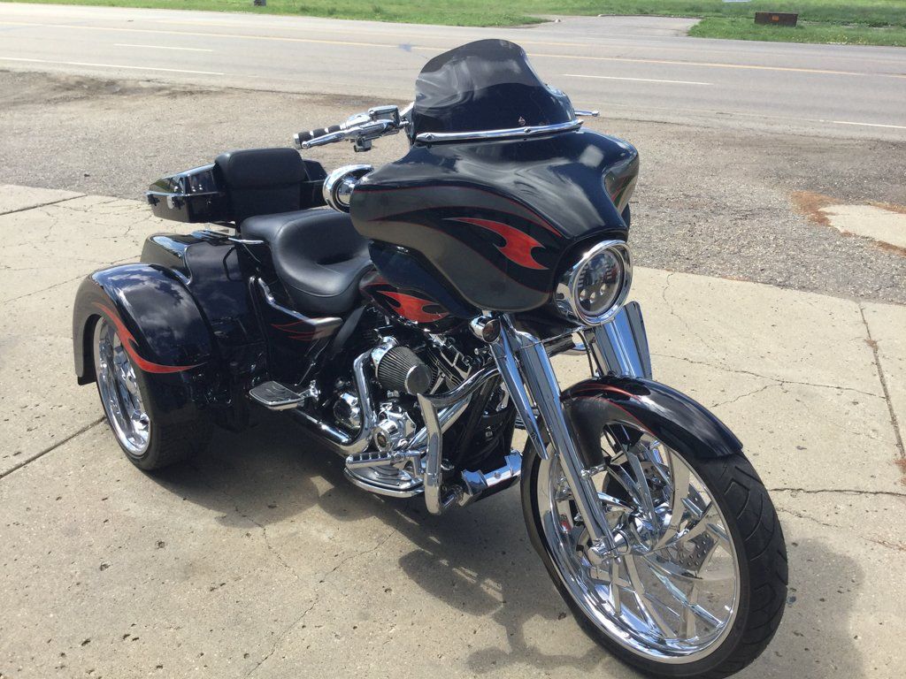 front side view of customized black three wheel motorcycle on sidewalk