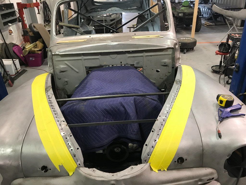 car hood with moving blanket on top of car engine with yellow tape