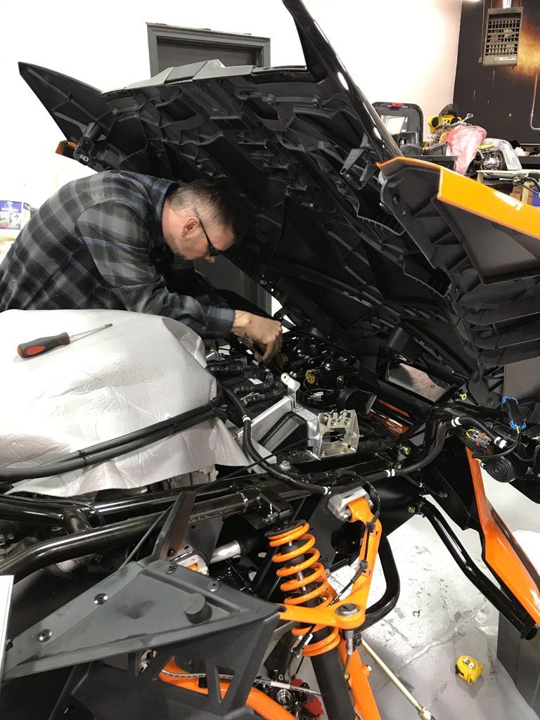 mechanic working on custom orange and black polaris slingshot