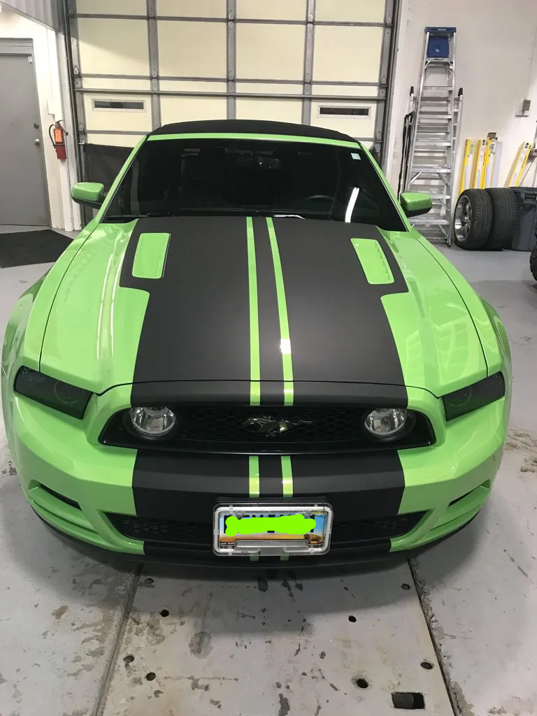 front view customized green mustang with black stripes in garage