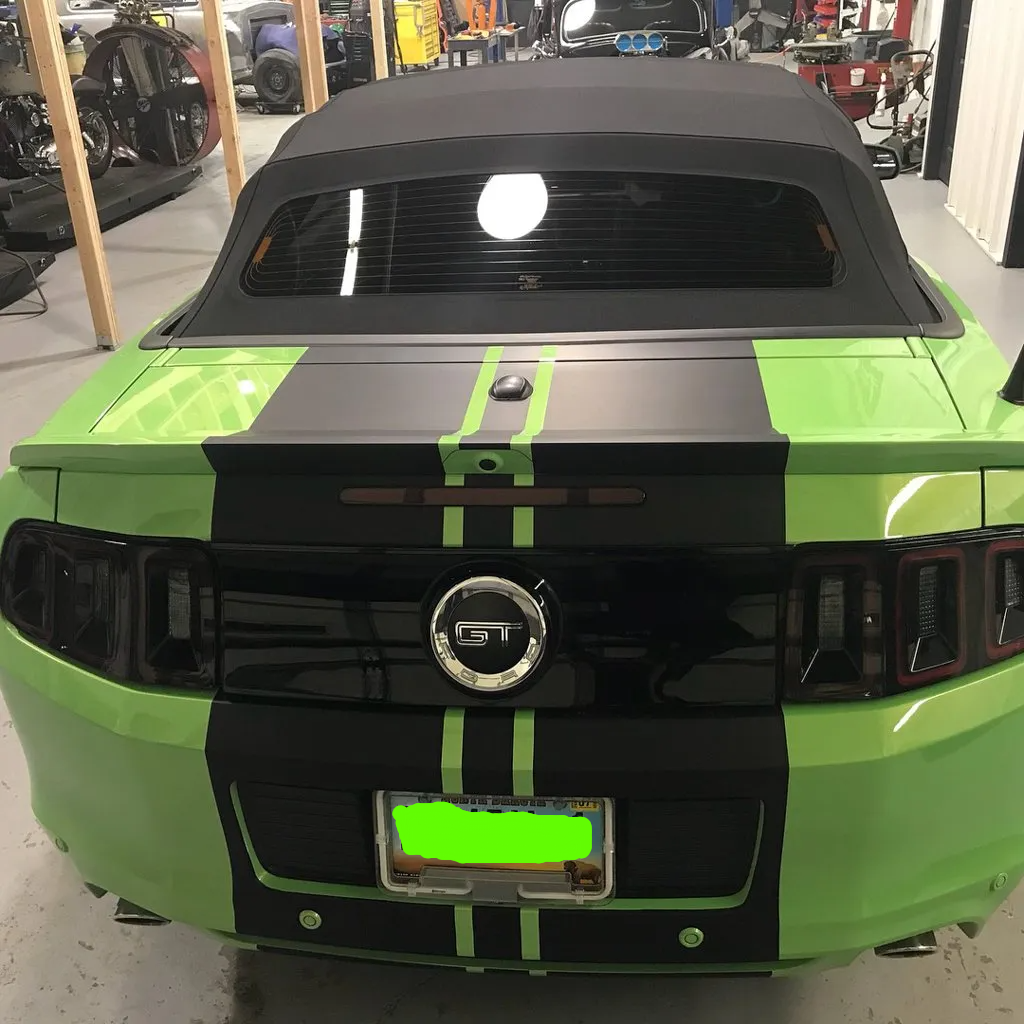 rear view customized green mustang with black stripes in garage