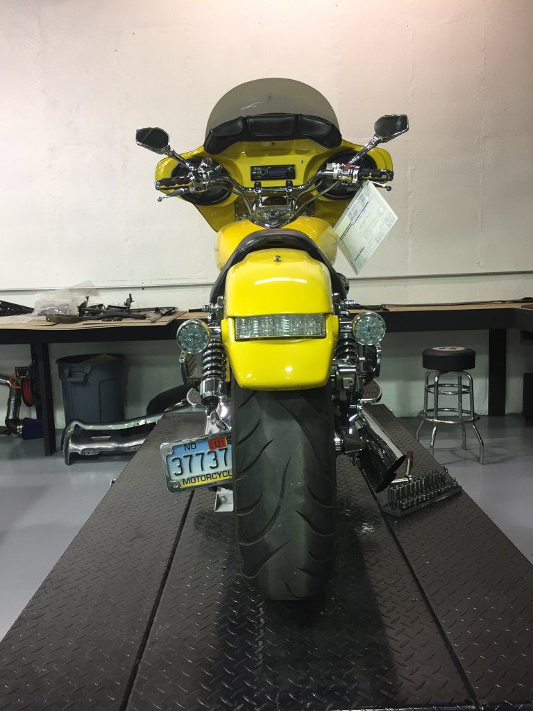 rear view of yellow motorcycle with license plate on raised on service bay