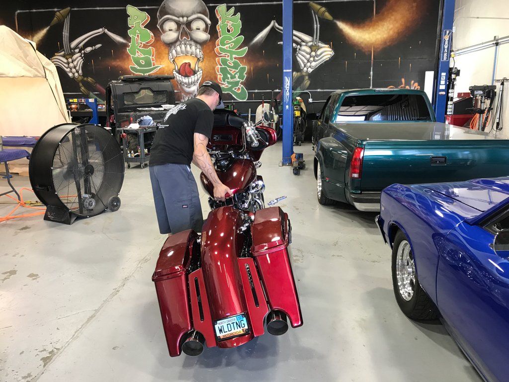 mechanic inspecting custom red and chrome motorcycle in garage
