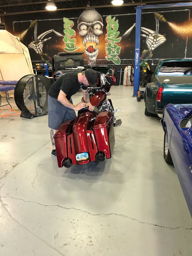 worker inspecting custom red and chrome motorcycle
