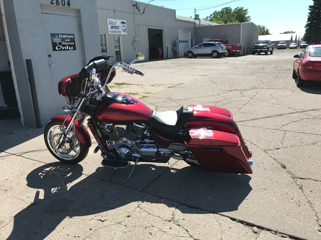 side view of rear view of customized red and chrome motorcycle in garage with dakota kustomz graffiti art in front of garage