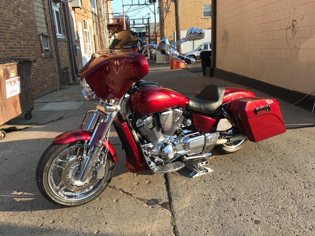 front side view of rear view of customized red and chrome motorcycle in garage with dakota kustomz graffiti art