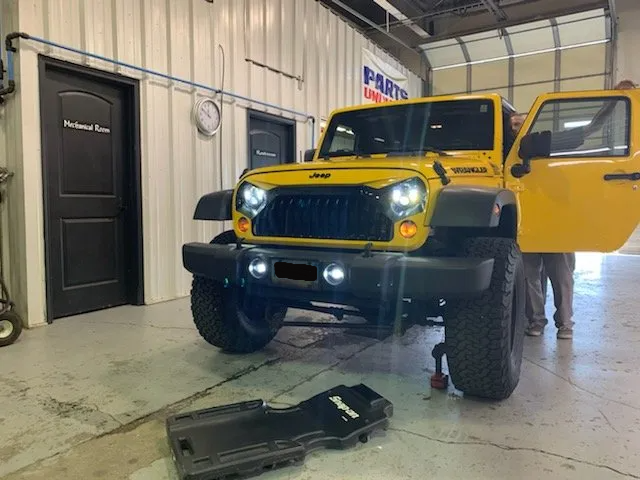 bigger view of yellow jeep with lights on in garage
