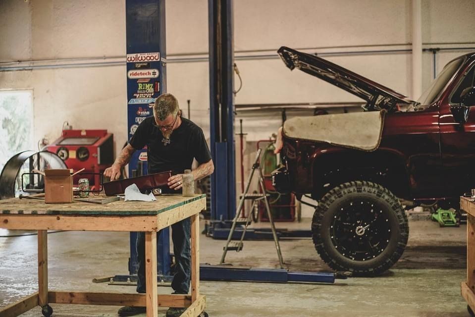 Mechanic inspecting a custom truck part on wooden workbench