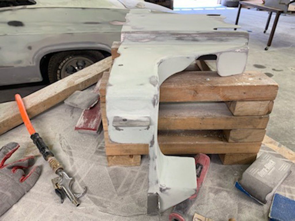 side view of painted car part suspended on wooden crate