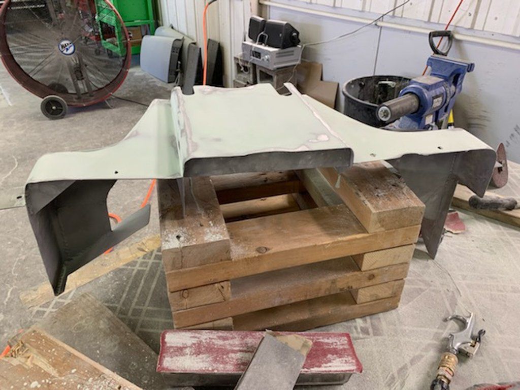 painted car part suspended on wooden crate