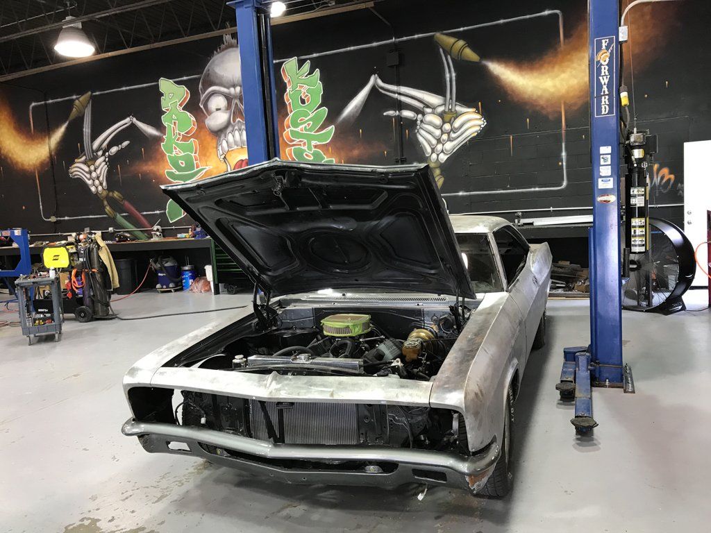 car in service bay with hood open, front grill missing