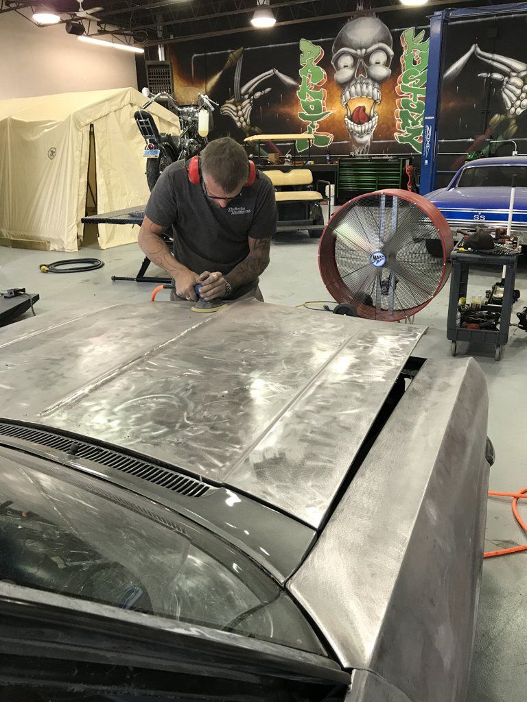 closers passenger side view of mechanic buffering car hood