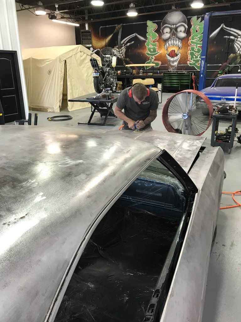 passenger side view of mechanic buffering car hood