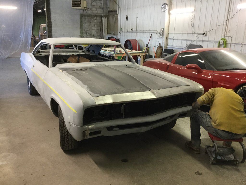 front view of car missing front grill with mechanic inspecting car
