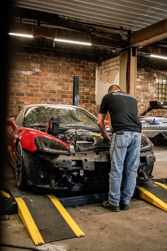 mechanic working on corvette with fender and hood removed