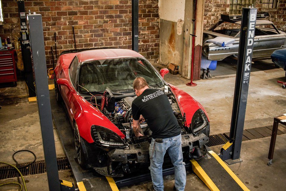 mechanic working on corvette with fender and hood removed