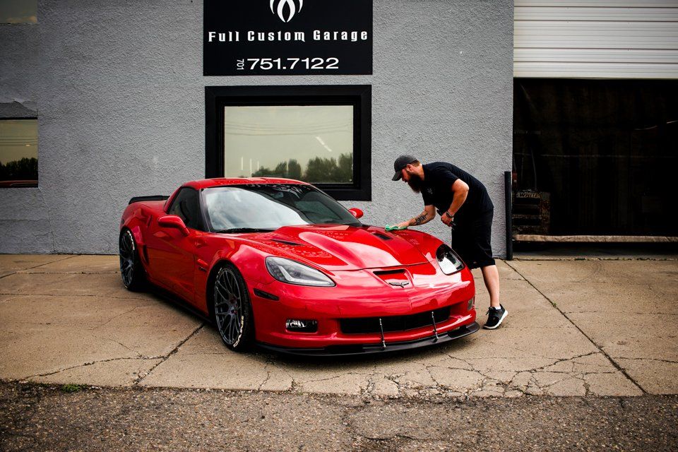 custom red 2006 corvette car in front of store with worker