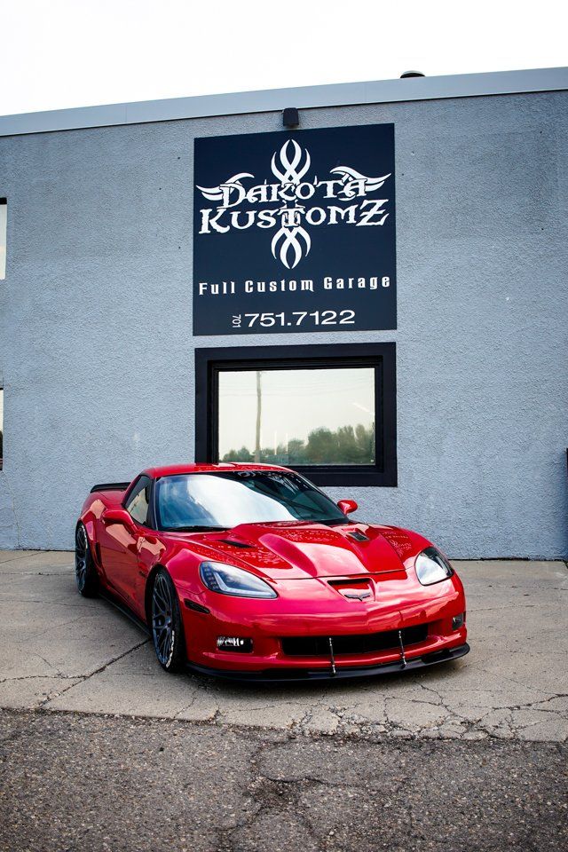 custom red 2006 corvette car in front of dakota kustomz store